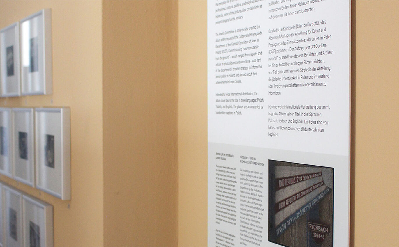 Nahaufnahme einer Informationstafel vor einer orangenen Wand.