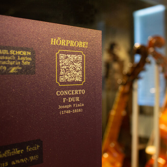 Nahaufnahme einer Scheibenfolie mit Textaufdruck. Zu sehen ist ein QR-Code über dem "Hörprobe" steht. Darunter ist der Name des Musikstückes sowie der oder die Interpret/Interpretin und das Jahr.
