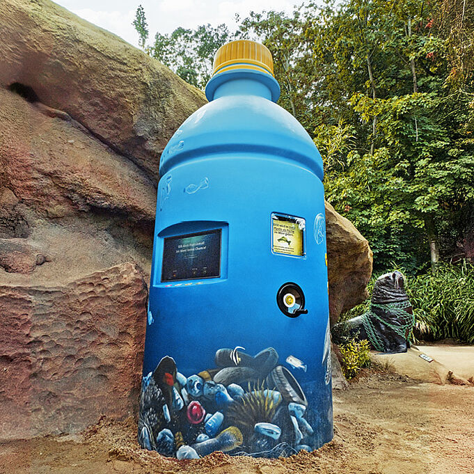 Foto der blauen nachgebildeten Plastikflasche. Links ist ein Bildschirm eingelassen.
