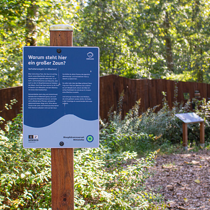 Blue information sign explains why there is a fence