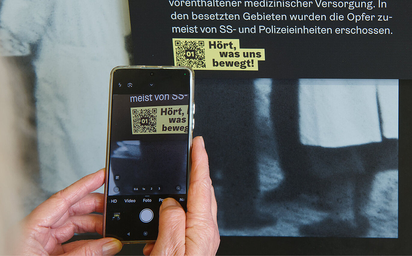 Eine Person fotografiert einen QR-Code mit ihrem Handy.
