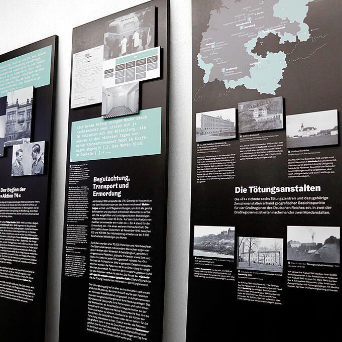 Three exhibition panels lean against a white wall