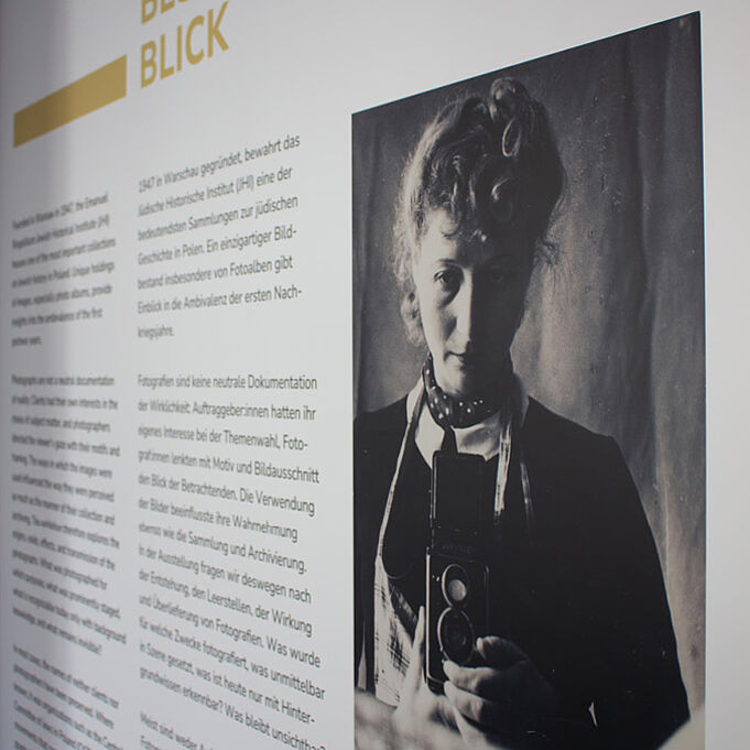Die erste Informationstafel vom Anfang in Nahaufnahme. Die schwarz-weiß Fotografie einer jungen Frau ist zu erkennen. Daneben steht Text.