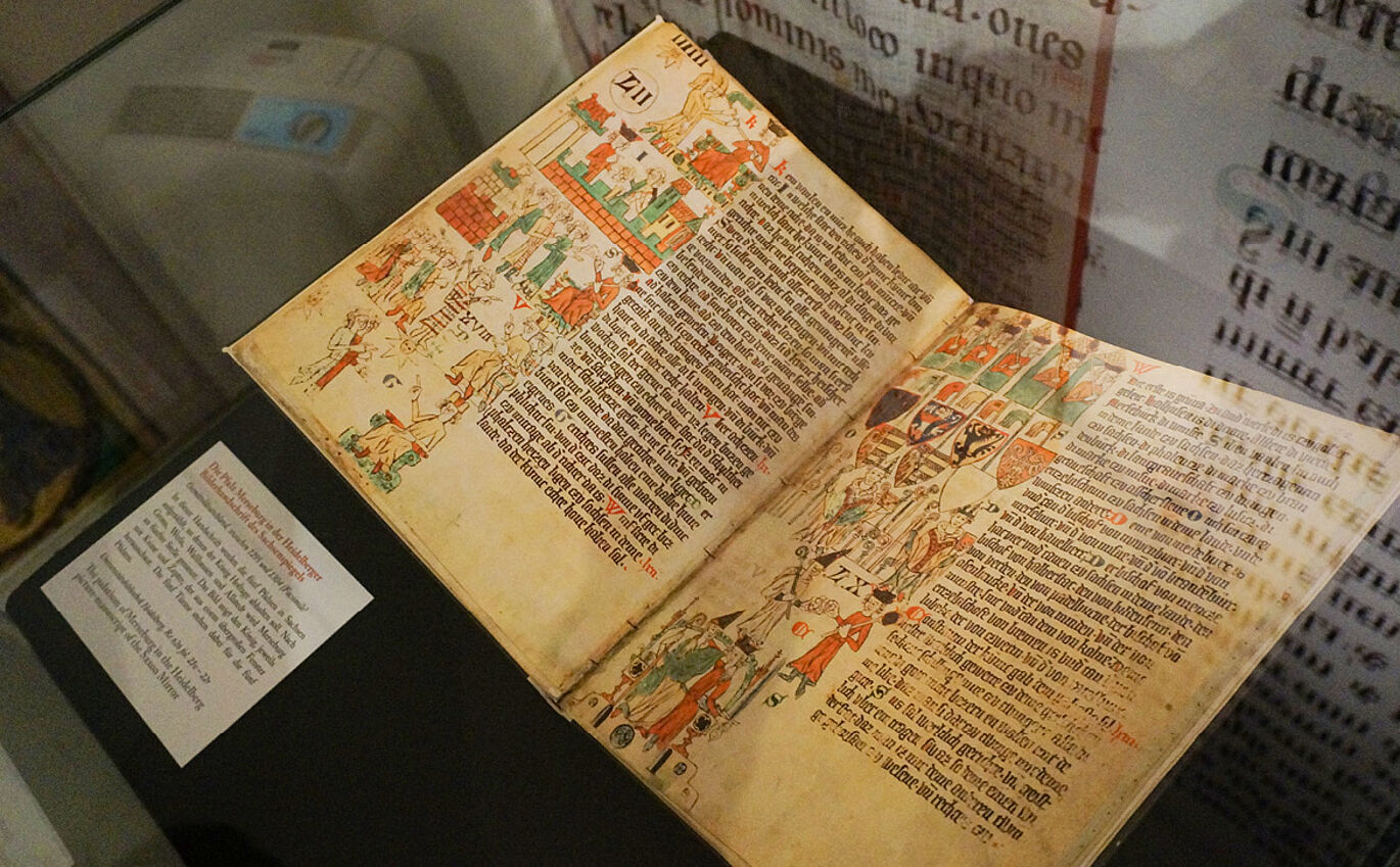 Die Pfalz Merseburg in der Heidelberger Bilderhandschrift des Sachsenspiegels, Schriftstück liegt aufgeschlagen in der Vitrine