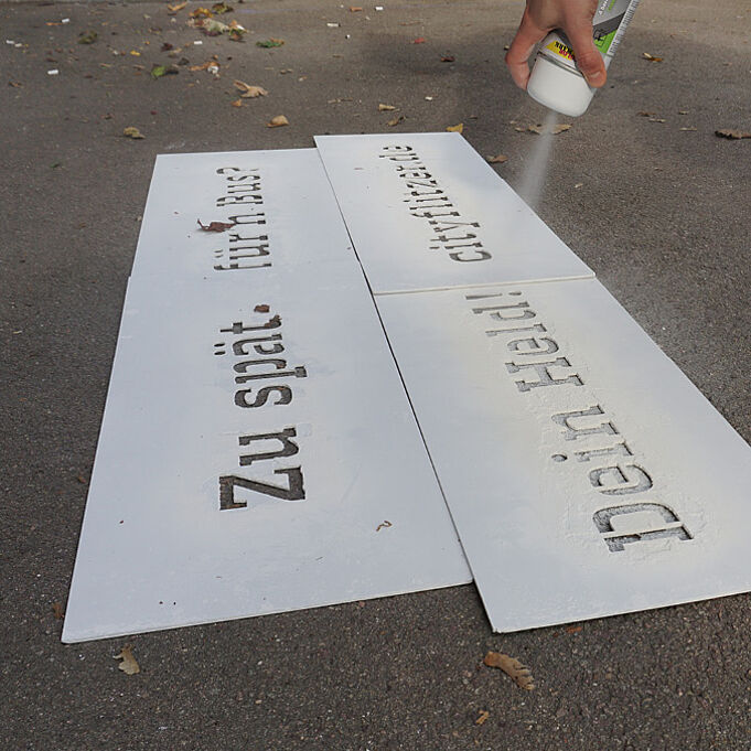 Lettering in the corporate design of cityflitzer sprayed on the road with white paint 