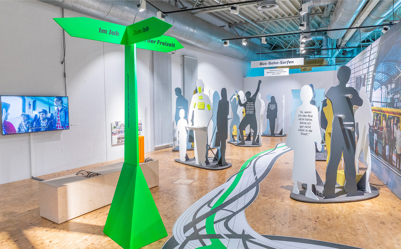 Figures of various people distributed in a room as part of scenographic exhibition design 