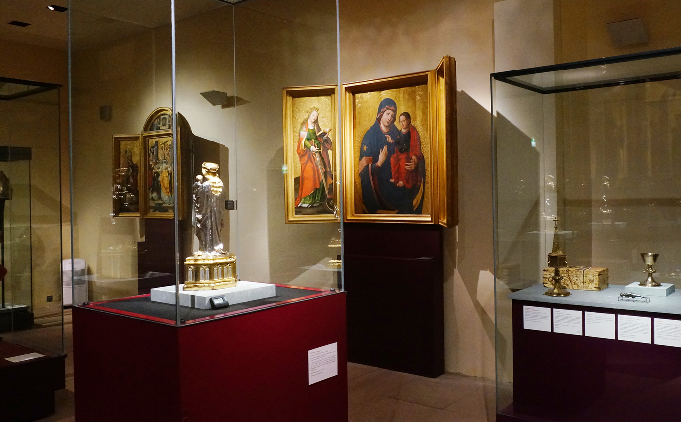 Ausstellungssituation: Exponate in Vitrinen und Altarbilder an Wänden