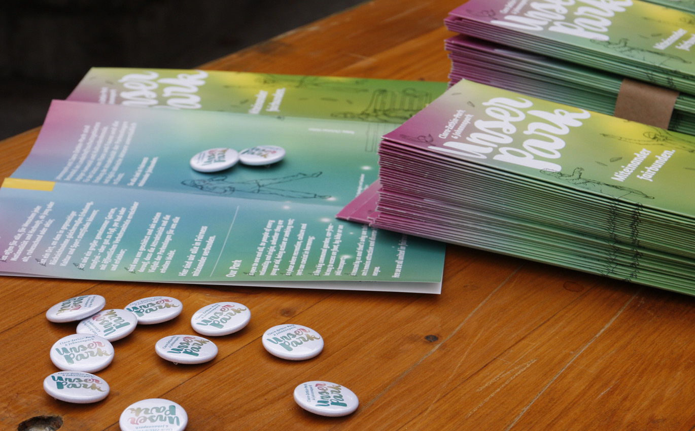 Flyers and buttons from the "Our Park" communication campaign are laid out on a table
